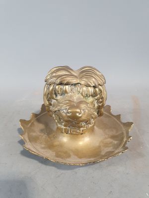 une assiette en or ornée d'une tête de lion, posée sur un fond blanc