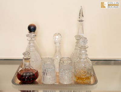 quatre bouteilles d'alcool posées sur un plateau en argent, sur une table