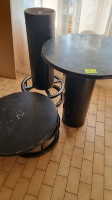 a black table and two stools on a tiled floor