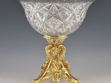 a glass bowl on a gold stand on a gray background