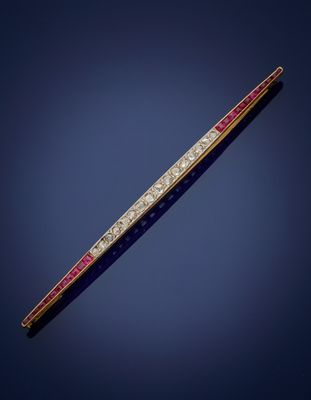 a gold, diamond and ruby bar broochle on a blue background