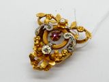 a gold brooch with a red stone in it