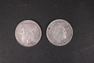 two silver coins sitting side by side on a black surface