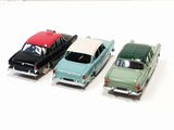 three toy cars are lined up in a row on a white surface
