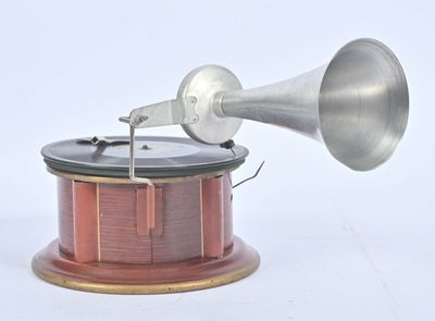 une enceinte argentée et rouge posée sur un socle en bois