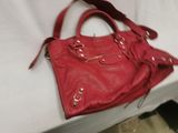red leather handbag sitting on a bed with a white sheet