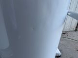 a white coffee pot sitting on the ground next to a window