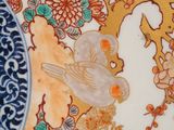 a close up of a plate with a bird and flowers on it