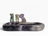 trois figurines d'animaux posées sur une pierre