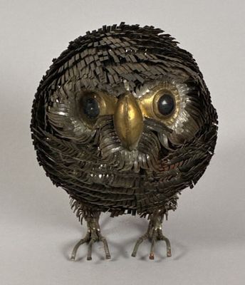 an owl made out of metal pieces on a white surface