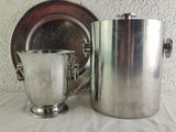 a silver cup next to a silver pitcher on a table