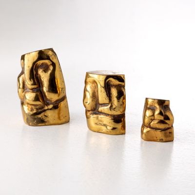 trois figurines en or posées sur une surface blanche