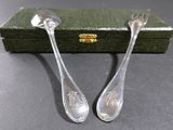two silver spoons sitting next to each other on a table