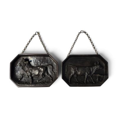 deux plaques métalliques ornées d'animaux, suspendues à une chaîne