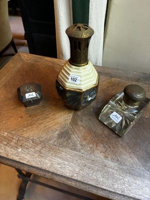 une petite table sur laquelle se trouvent un vase et deux flacons de parfum