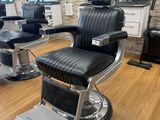 black and chrome barber chair in front of a mirror in a barber shop