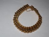 a close up of a gold chain bracelet on a white surface