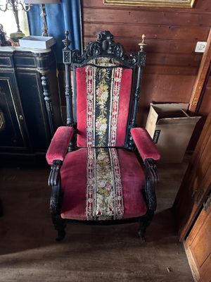 a red and black chair in a room with a painting on the wall