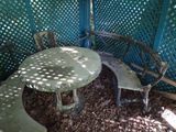 a table and two chairs in the shade of a tree