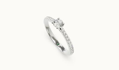 une bague sertie d'un diamant et d'une émeraude sur fond blanc