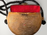 an old gold purse with a red velvet lining on a rope