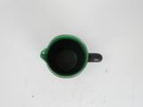 a green cup with a black handle on a white table
