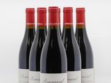 quatre bouteilles de vin rouge sont alignées sur une surface blanche