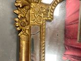 a mirror with a gold frame and a red curtain in the background