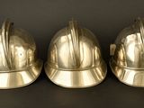 three shiny metal helmets sitting on top of a black surface