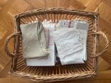 un panier rempli de vêtements pour bébé posé sur un parquet