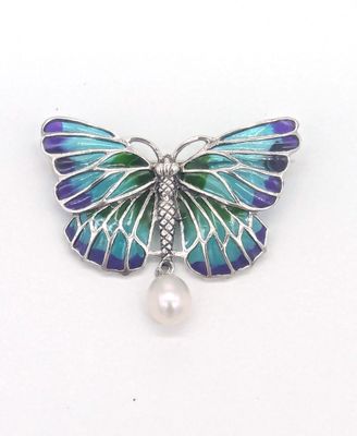 broche en forme de papillon violet et bleu ornée d'une perle sur fond blanc