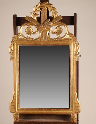 un miroir ancien en bois posé sur un pied, avec un miroir au centre