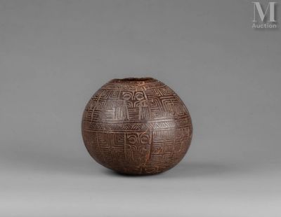 un vase marron posé sur une table près d'un mur gris