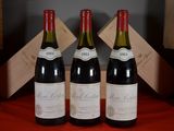 three bottles of red wine sit on a red table cloth