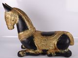 un cheval noir et doré posé sur une surface blanche