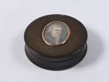 an old photo of a man in a suit sitting on a wooden box
