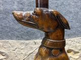statue of a dog with a candle in its mouth sitting on a rock