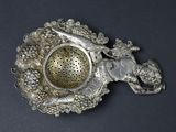 a silver tea strainer with a horse and a bird on it