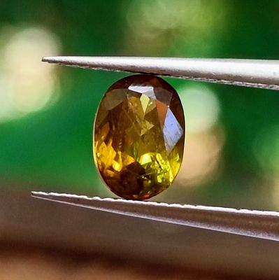 a close up of a yellow diamond being held by a pair of pliers