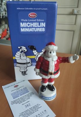 une figurine du Père Noël posée sur une table, à côté d'une boîte de miniatures Michel