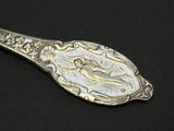 silver spoon with a picture of a woman on it on a black surface