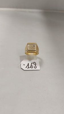 gros plan d'une chevalière en or sur une surface blanche