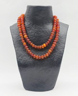 un gros plan d'un collier orné de perles orange sur un mannequin