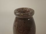 a brown vase sitting on a table with a white wall in the background