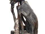 statue d'un homme assis sur une chaise, coiffé d'un chapeau et tenant un sac à la main