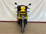 a yellow motorcycle parked in front of a white wall