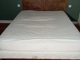 a bed with a wooden headboard and white sheets on it