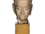 statue représentant une tête de Bouddha posée sur un socle en bois, sur fond blanc