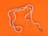 an orange background with a white pearl necklace and a gold clasp