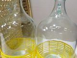two yellow glass vases sitting on a table next to a wicker chair
